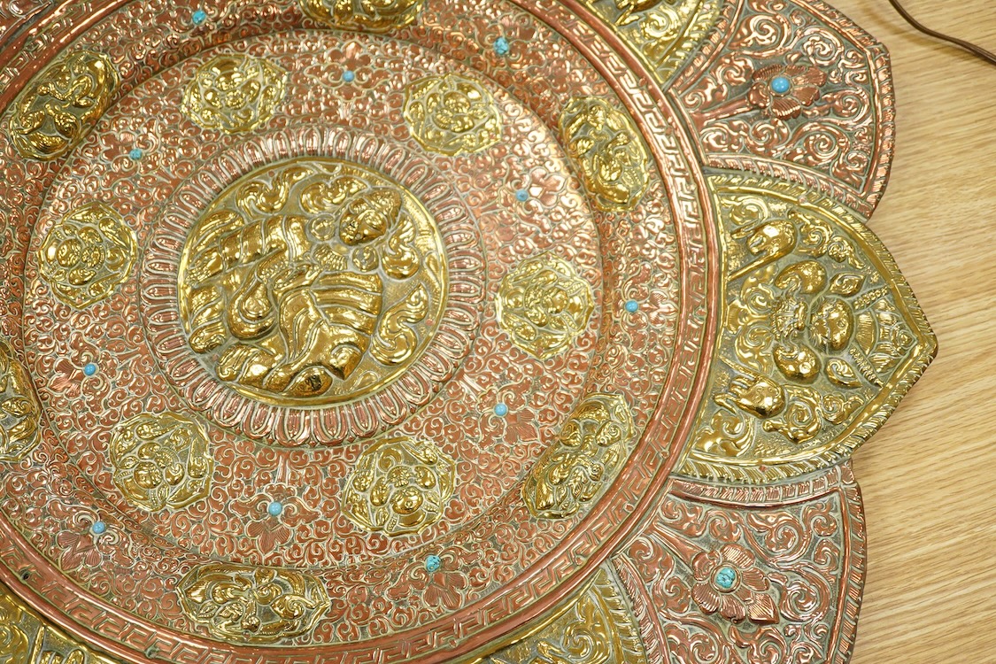 A large Nepalese brass and copper embossed tray, first half 20th century, set with simulated turquoise cabochons, 68cm diameter